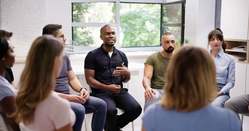 Young Multiracial Millennial Friends Sitting In Circle Having Group Discussion