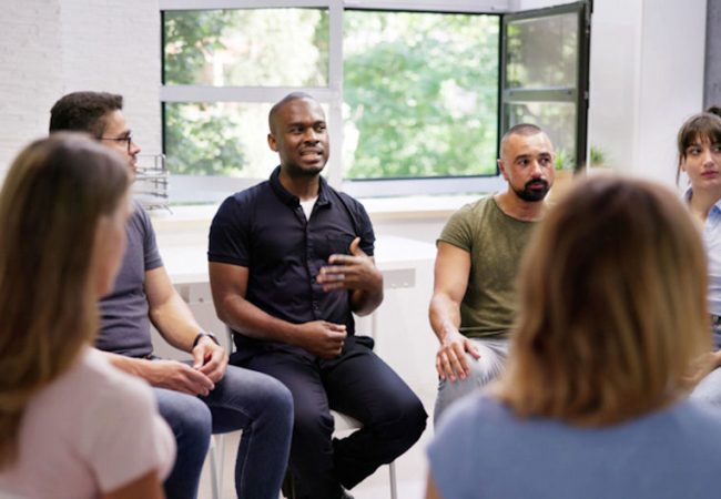 Young Multiracial Millennial Friends Sitting In Circle Having Group Discussion